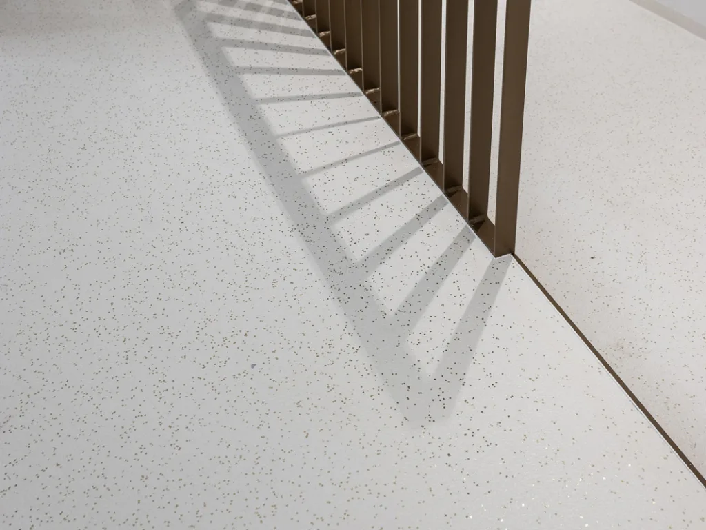 Epoxidharzbeschichtung mit Farbchips in Gold und Geländer in Bronze